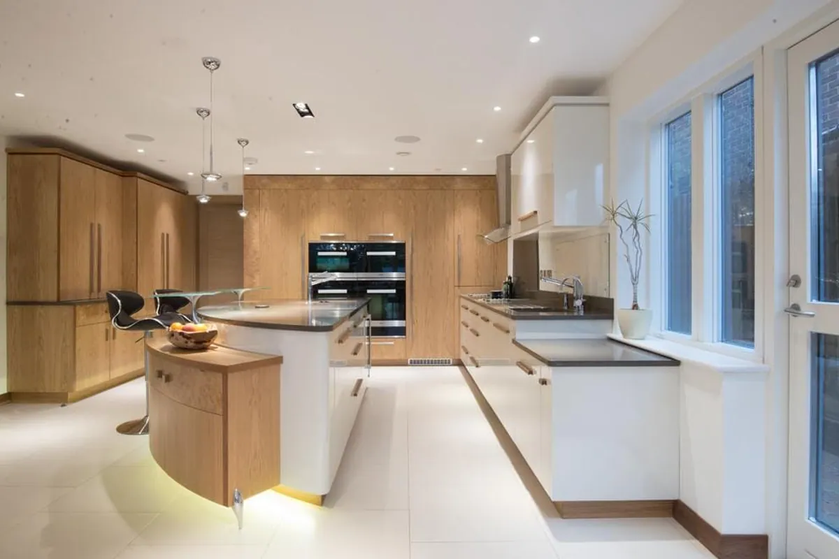 Open-plan kitchen with oak and white units and a curved island, London